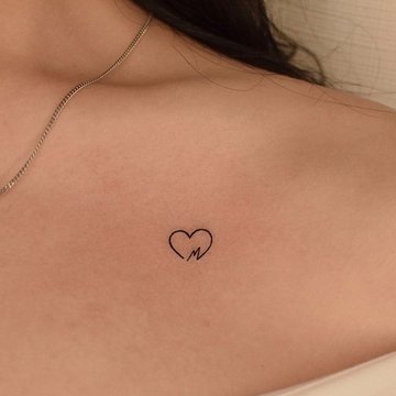 Tattoo Herz mit Buchstabe in feinem Linienstil auf dem Schlüsselbein