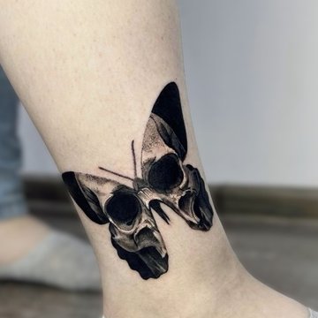 Schmetterling mit Totenkopf auf der Wade