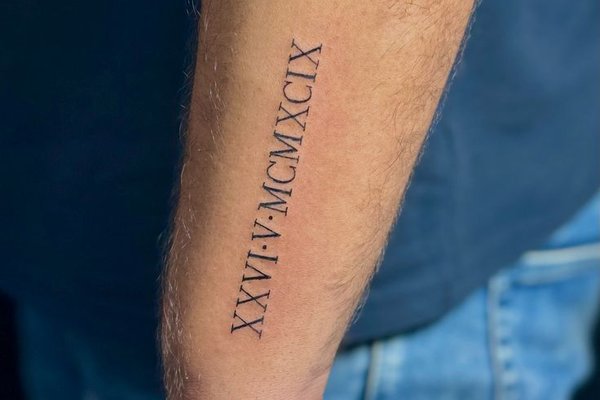 Schlichtes Tattoo mit römischen Zahlen an der Hand