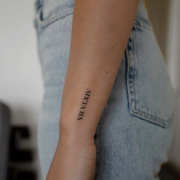 Römische Zahlen als Teil eines Armbandes tätowiert