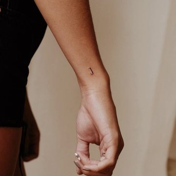 Minimalistisches Buchstaben Tattoo am Handgelenk