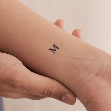 Feines Buchstabe M Tattoo am Handgelenk