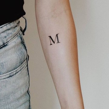 Tätowierter Buchstabe M mit Flügeln