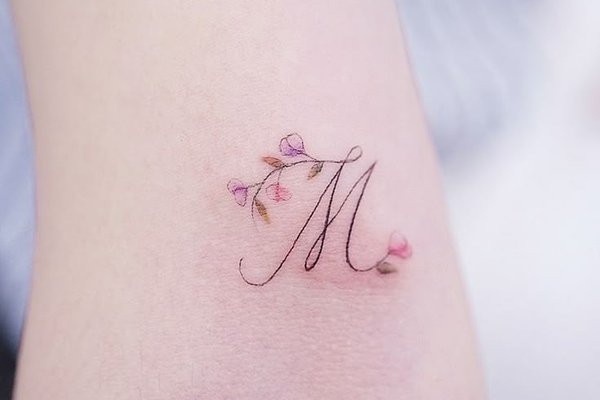 M mit floralen Ornamenten als Tattoo