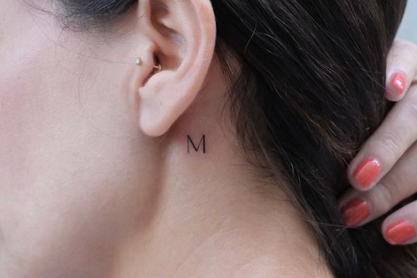 Buchstabe M hinter dem Ohr tätowiert