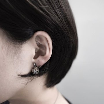 Minimalistisches Tattoo eines Semikolons hinter dem Ohr