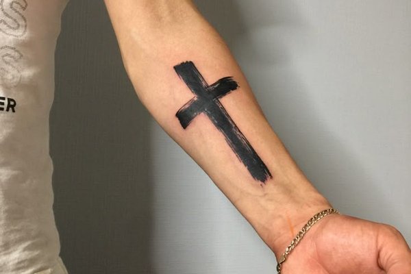 Kreuz in gotischer Schrift tätowiert an der Hand
