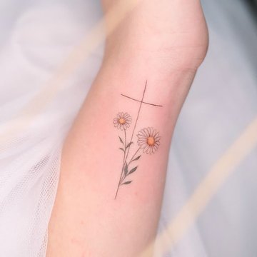 Kleines Kreuz Tattoo auf dem Handgelenk bei Tageslicht