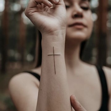 Feines Kreuz Tattoo auf der rechten Hand mit Bedeutung